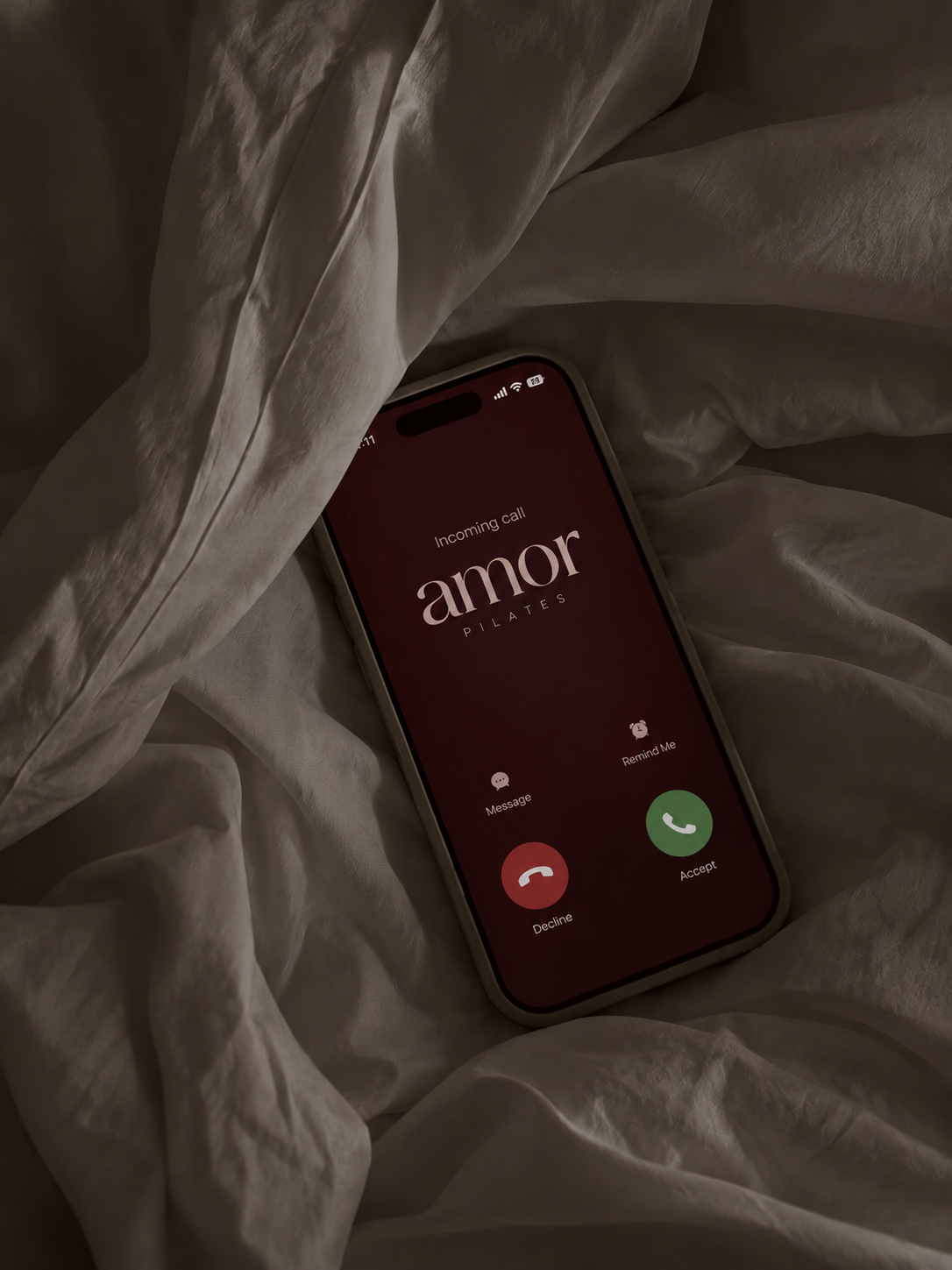 Phone on linen sheets showing an incoming call from Amor Pilates.